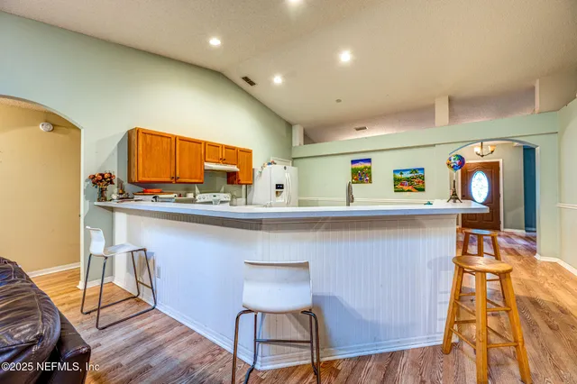 a kitchen with stainless steel appliances kitchen island granite countertop a stove a dining table and chairs with wooden floor