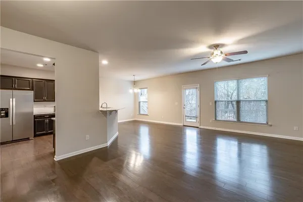 a view of an empty room with a kitchen and wooden floor