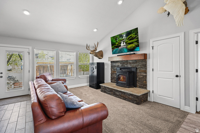 1588 West Rim Rock Drive Stockton, UT 84071 - Photo 8 of 61 Spacious living area featuring a stone-clad fireplace with a wood mantel, vaulted ceiling, recessed lighting, and multiple windows with blinds