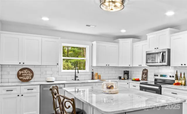 a kitchen with stainless steel appliances granite countertop a sink a stove a window cabinets and a window