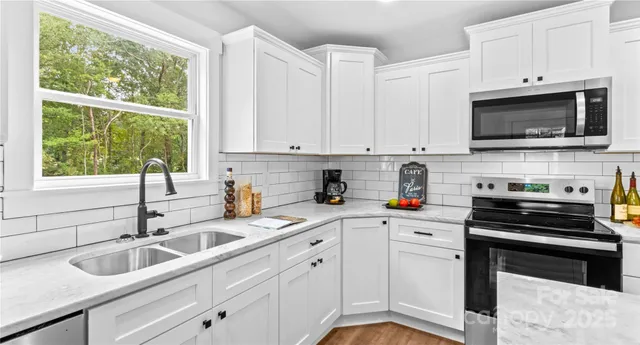 a kitchen with stainless steel appliances white cabinets a sink and a stove