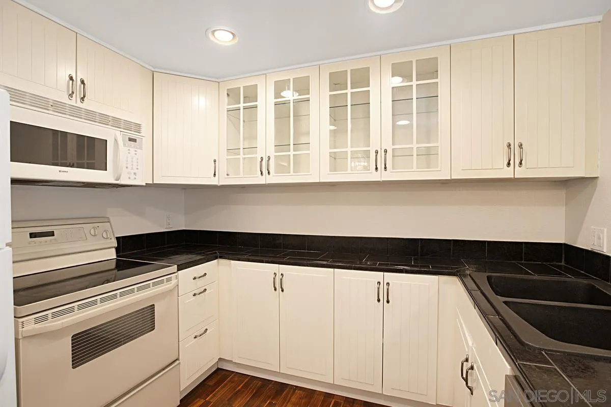 5906 Rancho Mission Road, Unit 5 San Diego, CA 92108 - Photo 13 of 33 a kitchen with granite countertop white cabinets and sink