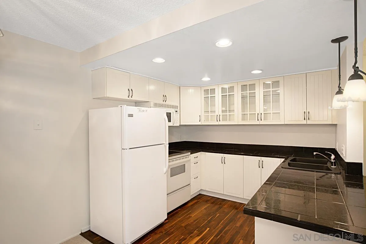 5906 Rancho Mission Road, Unit 5 San Diego, CA 92108 - Photo 3 of 33 a kitchen with granite countertop a refrigerator a sink and wooden floors