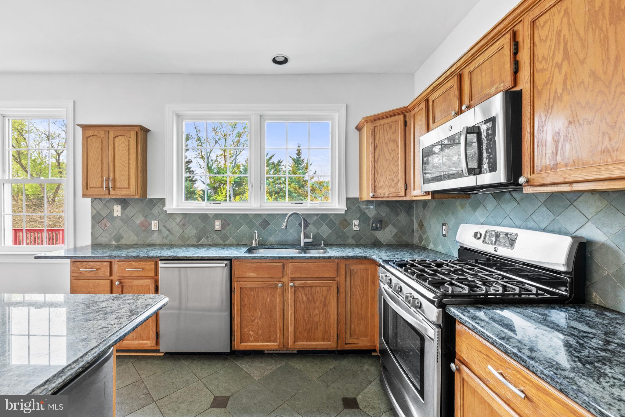 409 Midsummer Drive Gaithersburg, MD 20878 - Photo 9 of 41 a kitchen with stainless steel appliances granite countertop a stove a sink and a microwave