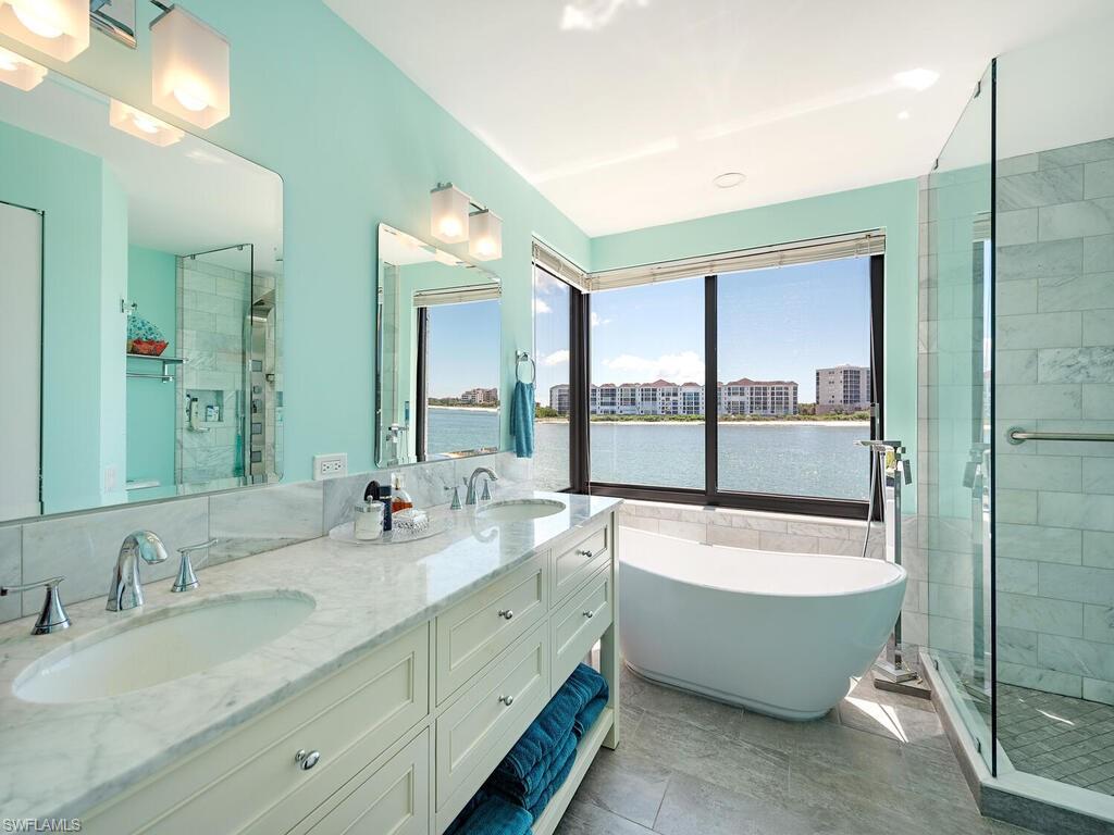421 La Peninsula Boulevard, Unit 421 Naples, FL 34113 - Photo 8 of 18 a bathroom with a tub sink and mirror