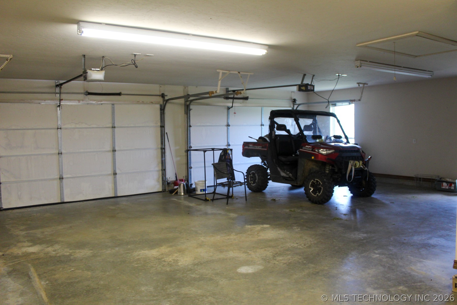13248 North 3540th Road Maud, OK 74854 - Photo 86 of 98 Spacious garage featuring two overhead doors, a concrete floor, and overhead fluorescent lighting