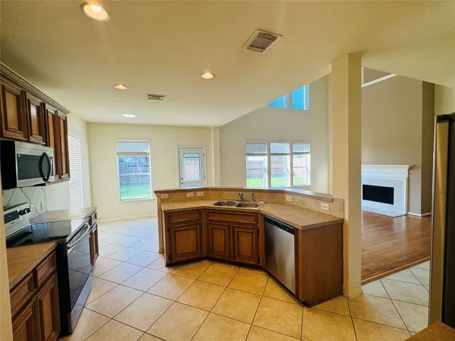 a kitchen with stainless steel appliances granite countertop a sink and a stove top oven with wooden floor