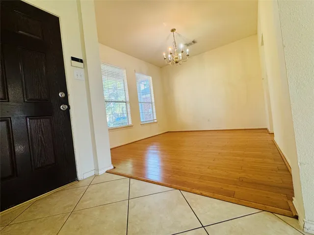 a view of an empty room with wooden floor and a carpet