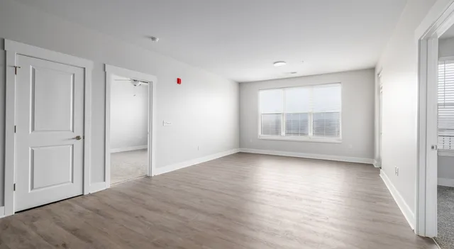 an empty room with wooden floor and windows
