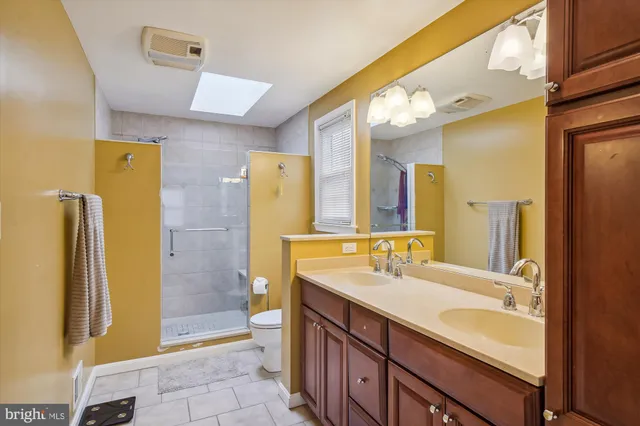 a bathroom with a sink a toilet a mirror and shower