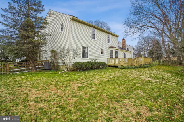 a white house that has a big yard plants and large trees