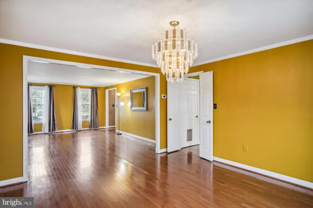 a view of an empty room with wooden floor and chandelier