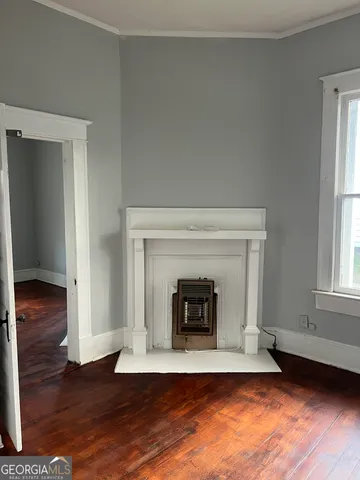an empty room with wooden floor a fireplace and windows