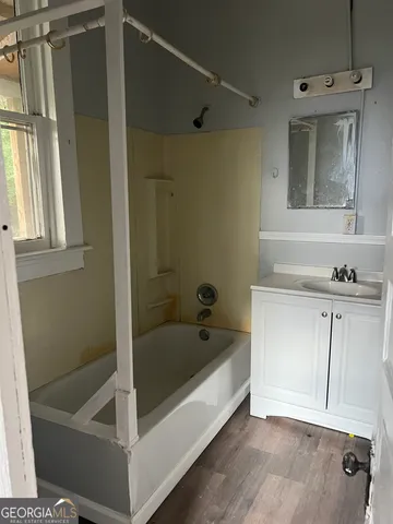 a bathroom with a tub a sink and a mirror