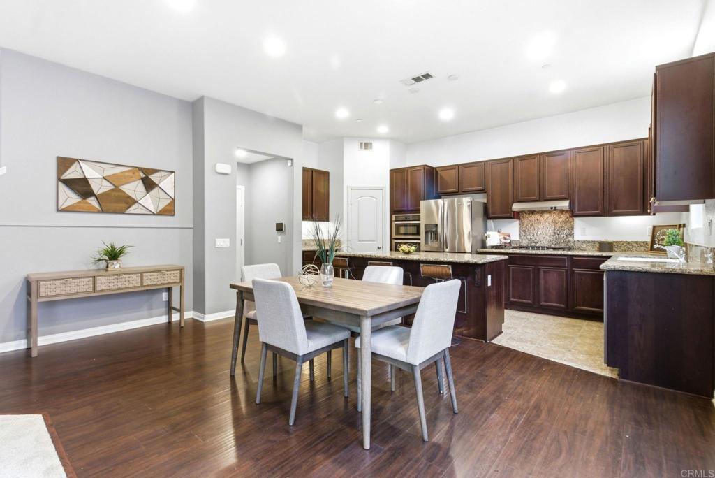 1508 Carpinteria Street Chula Vista, CA 91913 - Photo 9 of 39 a kitchen with stainless steel appliances kitchen island granite countertop a table chairs and a refrigerator