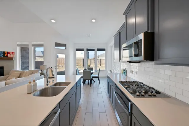 a kitchen with lots of counter top space a sink appliances and cabinets