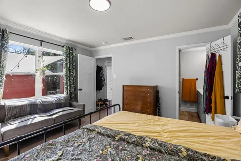 a bedroom with a bed and a dresser next to a window