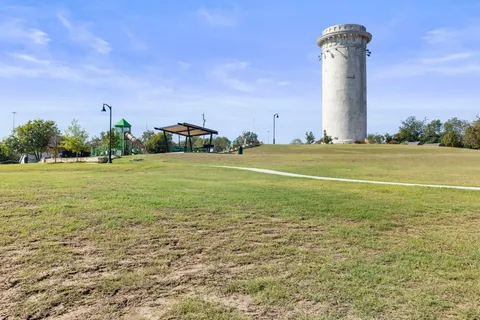 a view of a tall building with a big yard and large trees