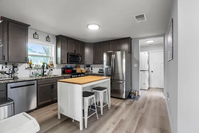 a kitchen with a refrigerator a sink dishwasher a stove and a refrigerator with wooden floor