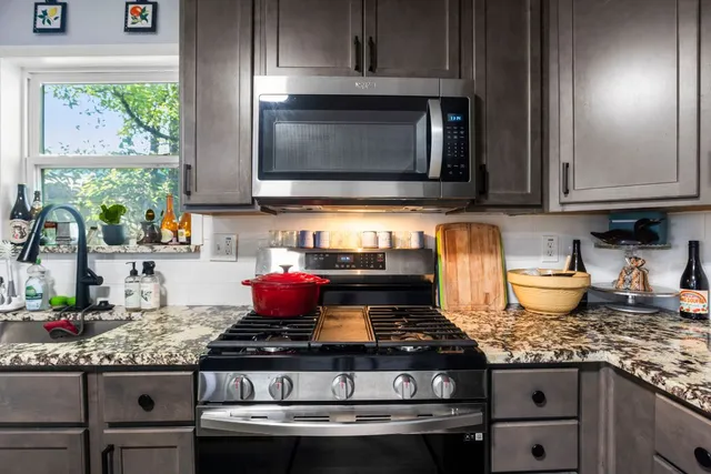 a kitchen with granite countertop a stove top oven microwave and cabinets