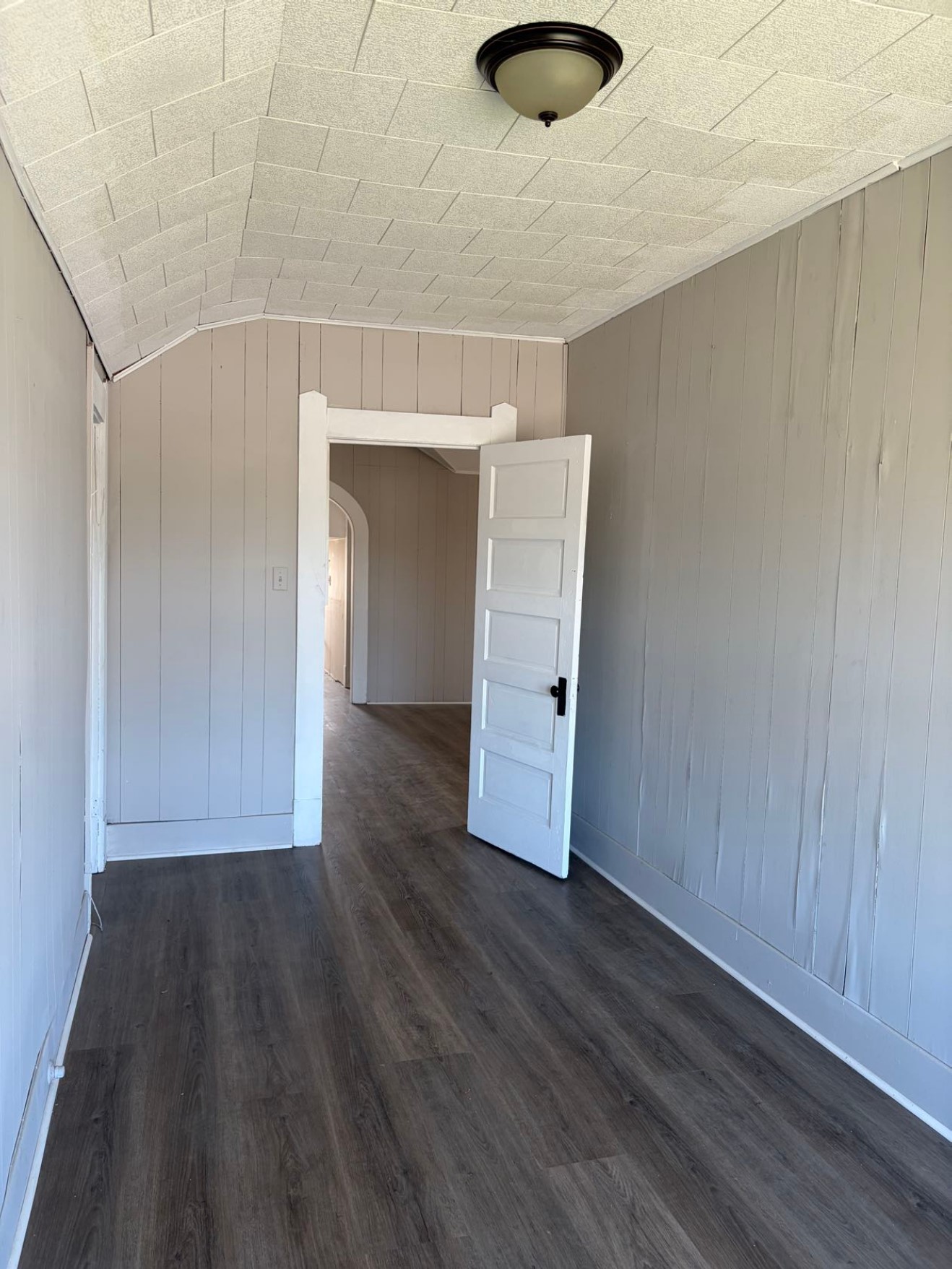 931 9th Avenue, Unit 2 Port Arthur, TX 77642 - Photo 6 of 9 Hallway -This room features neutral-toned walls, a textured ceiling, and dark wood-look flooring. It includes a white door leading to another area, creating a sense of openness.