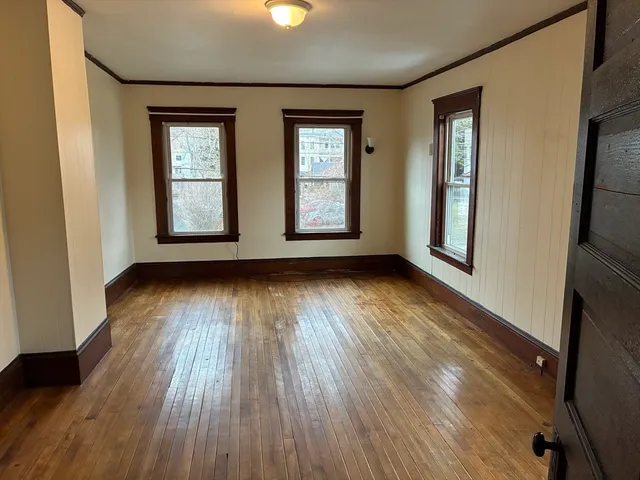 an empty room with wooden floor and windows
