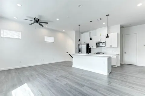 a large kitchen with white cabinets and wooden floor