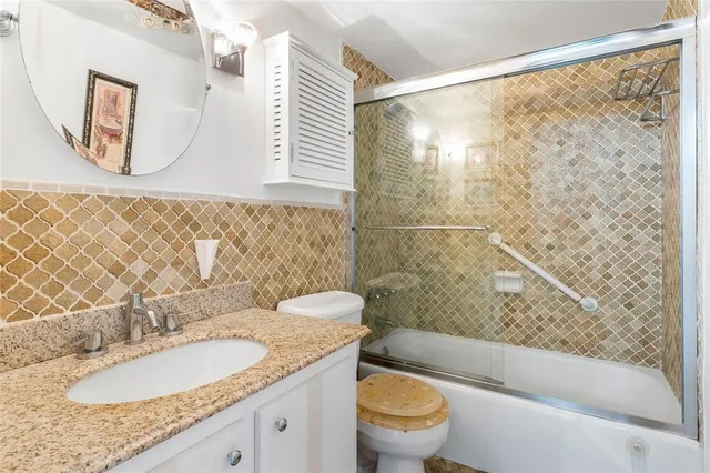 a bathroom with a granite countertop sink toilet and shower