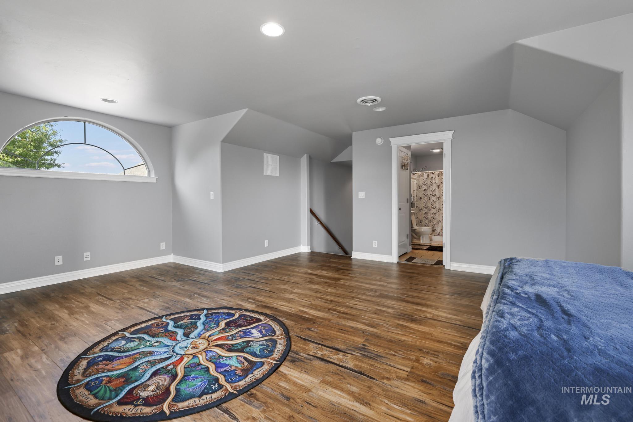 467 Wildrose Loop Twin Falls, ID 83301 - Photo 32 of 46 Spacious room featuring wood-finish flooring, a large arched window with grid detailing, recessed lighting, and an en-suite bathroom with a shower-tub combination