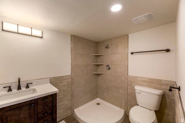 4658 Box Elder Street Salt Lake City, UT 84107 - Photo 6 of 17 Bathroom featuring a corner shower with built-in shelves, a dark wood-finish vanity with a white countertop, and a white sink with a dark bronze-finish faucet