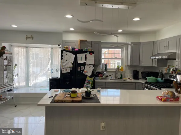 a view of a room with kitchen island stainless steel appliances a sink and a couch