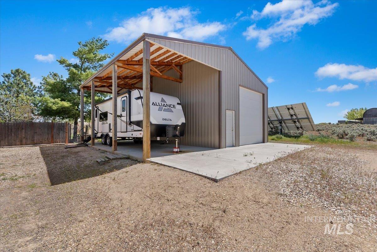 147 East Indian Crk Road Boise, ID 83716 - Photo 29 of 43 Metal building with an attached covered RV carport, a large roll-up door, a personnel entry door, and a concrete pad