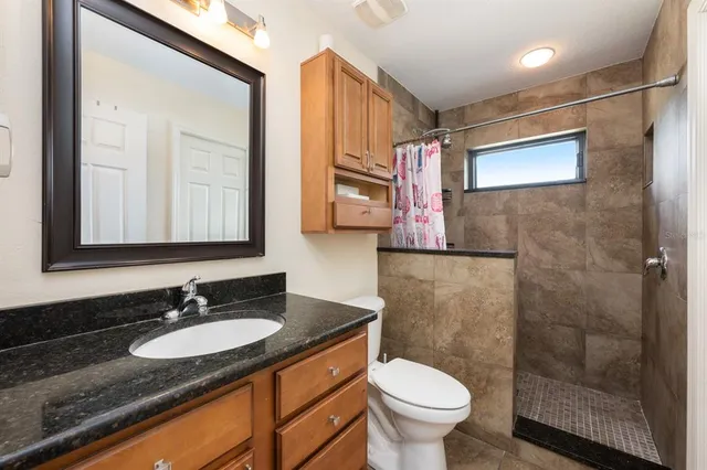 a bathroom with a granite countertop sink toilet and shower
