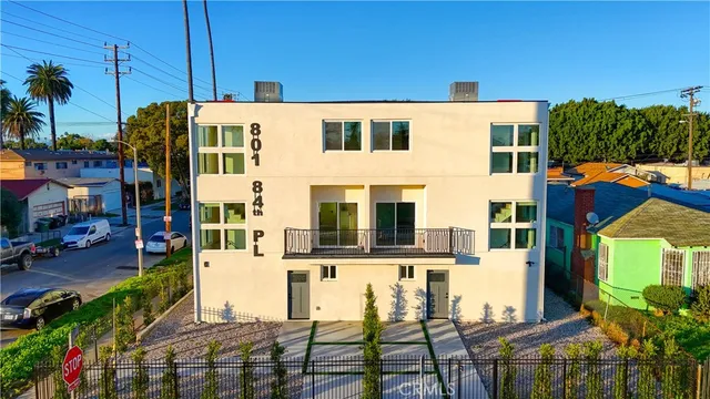 a view of a white building among the street with palm trees