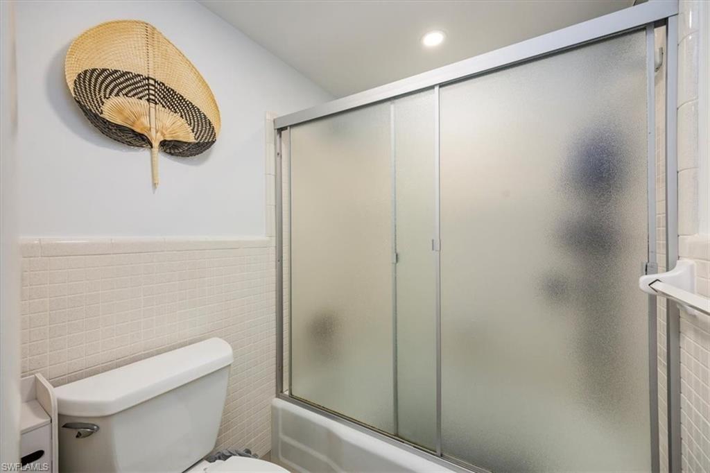 1900 Clifford Street, Unit 301 Fort Myers, FL 33901 - Photo 11 of 35 Full bathroom featuring tile walls, combined bath / shower with glass door, a wainscoted wall, and recessed lighting