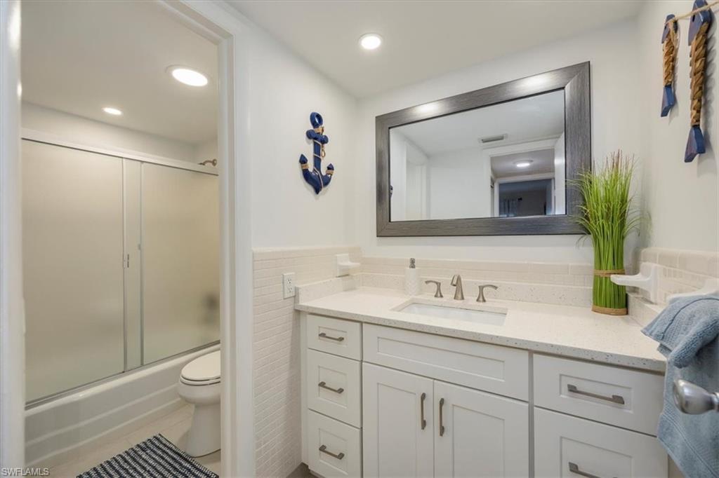 1900 Clifford Street, Unit 301 Fort Myers, FL 33901 - Photo 18 of 35 Full bathroom featuring vanity, tile walls, shower / bath combination with glass door, a wainscoted wall, and recessed lighting