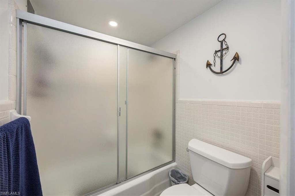 1900 Clifford Street, Unit 301 Fort Myers, FL 33901 - Photo 19 of 35 Bathroom with tile walls, enclosed tub / shower combo, wainscoting, and vanity