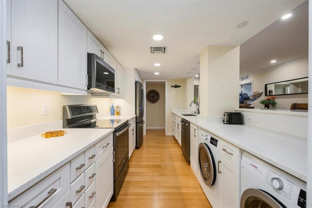 1900 Clifford Street, Unit 301 Fort Myers, FL 33901 - Photo 6 of 35 Kitchen with appliances with stainless steel finishes, washer / clothes dryer, white cabinetry, light wood-type flooring, and recessed lighting