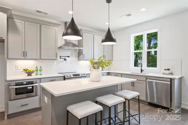 a kitchen with stainless steel appliances a sink a stove a refrigerator and cabinets