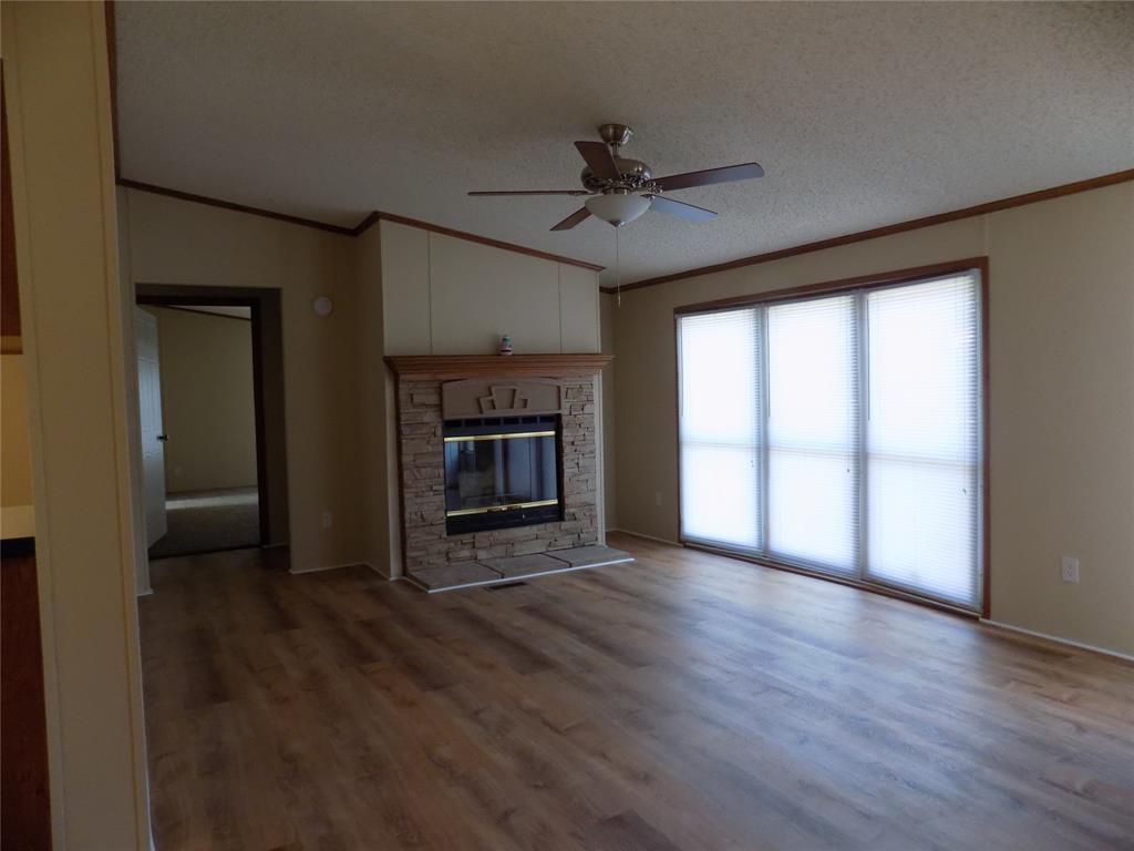 3450 Sarra Lane Springtown, TX 76082 - Photo 4 of 23 Lovely rock decorated fireplace in living room, with windows making the room light and bright.