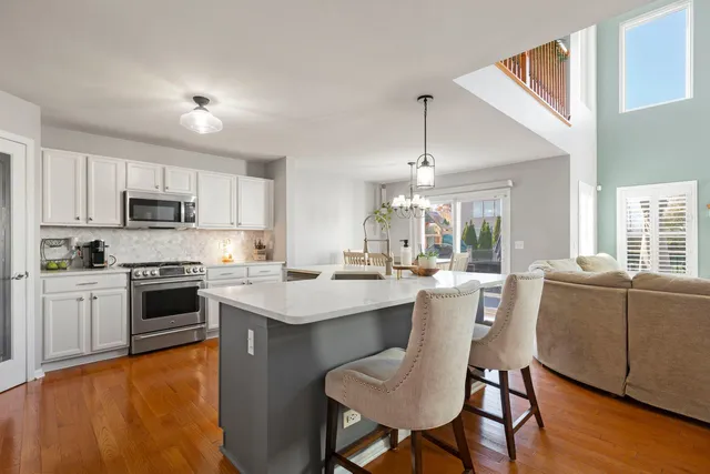 a kitchen with stainless steel appliances a stove a sink a kitchen island with a dining table and chairs