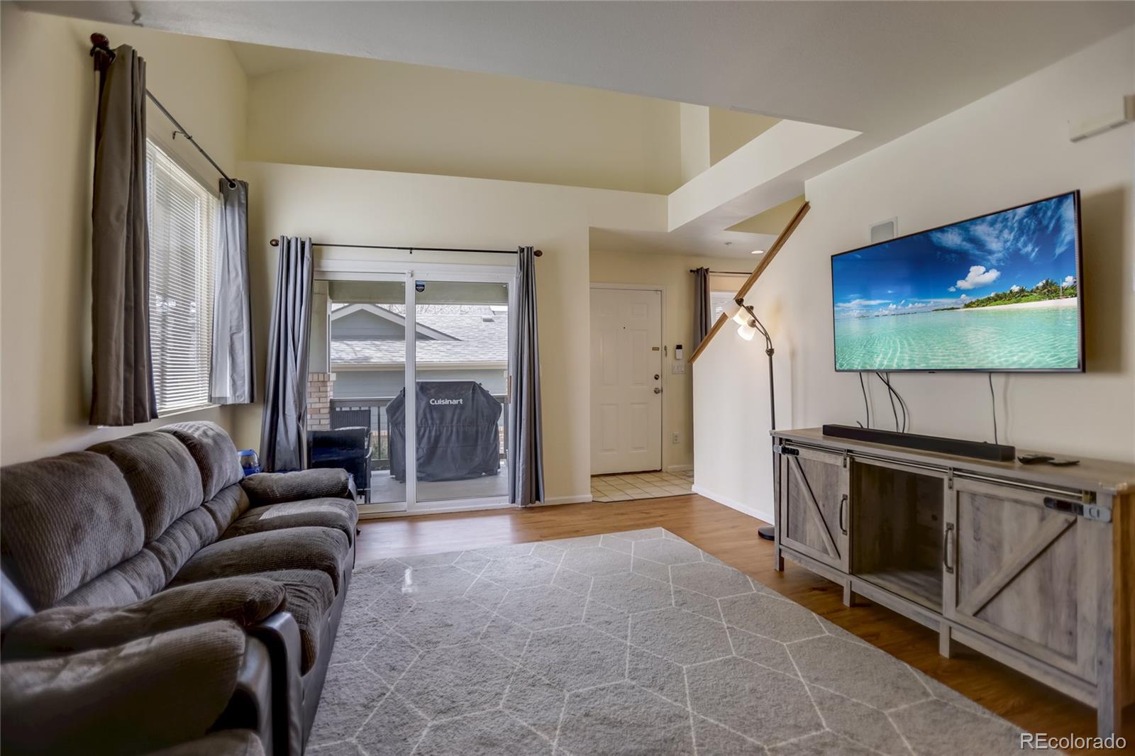 2900 Purcell Street, Unit O4 Brighton, CO 80601 - Photo 5 of 28 a living room with furniture a flat screen tv and a floor to ceiling window