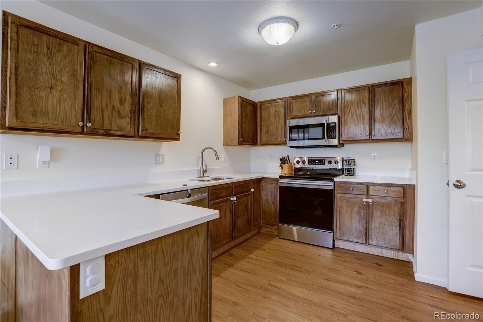 2900 Purcell Street, Unit O4 Brighton, CO 80601 - Photo 9 of 28 a kitchen with granite countertop wooden cabinets a stove and a microwave