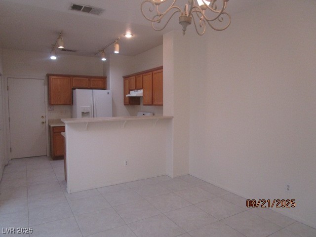 667 Solitude Point Avenue Henderson, NV 89012 - Photo 4 of 22 Kitchen featuring white refrigerator with ice dispenser, a kitchen breakfast bar, track lighting, light countertops, and a chandelier