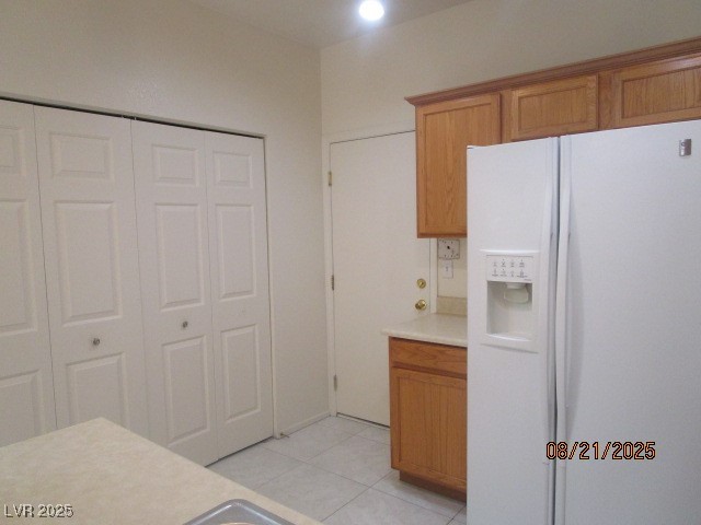 667 Solitude Point Avenue Henderson, NV 89012 - Photo 6 of 22 Kitchen with white refrigerator with ice dispenser, light countertops, light tile patterned floors, and brown cabinetry
