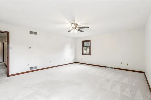 an empty room with a window and a ceiling fan