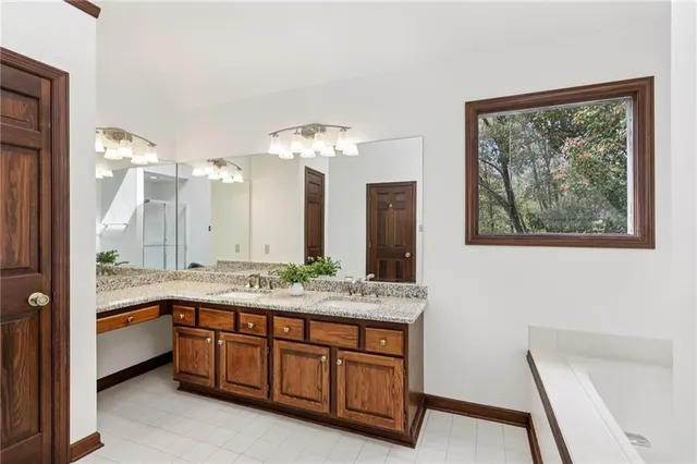 a spacious bathroom with a granite countertop sink a large mirror and a bathtub