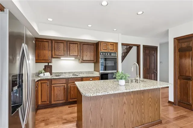 a kitchen with stainless steel appliances granite countertop a refrigerator a stove and a sink