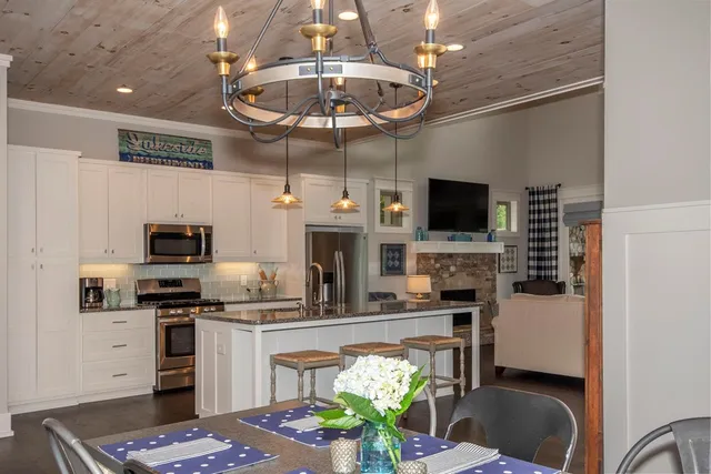 a kitchen with stainless steel appliances kitchen island granite countertop a refrigerator a stove top oven a sink and a island