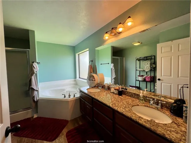 a bathroom with a granite countertop sink a large mirror and a bathtub